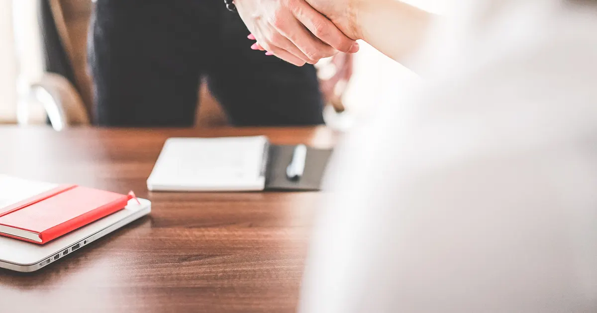 A broker and a developer shaking hands over a signed booking
